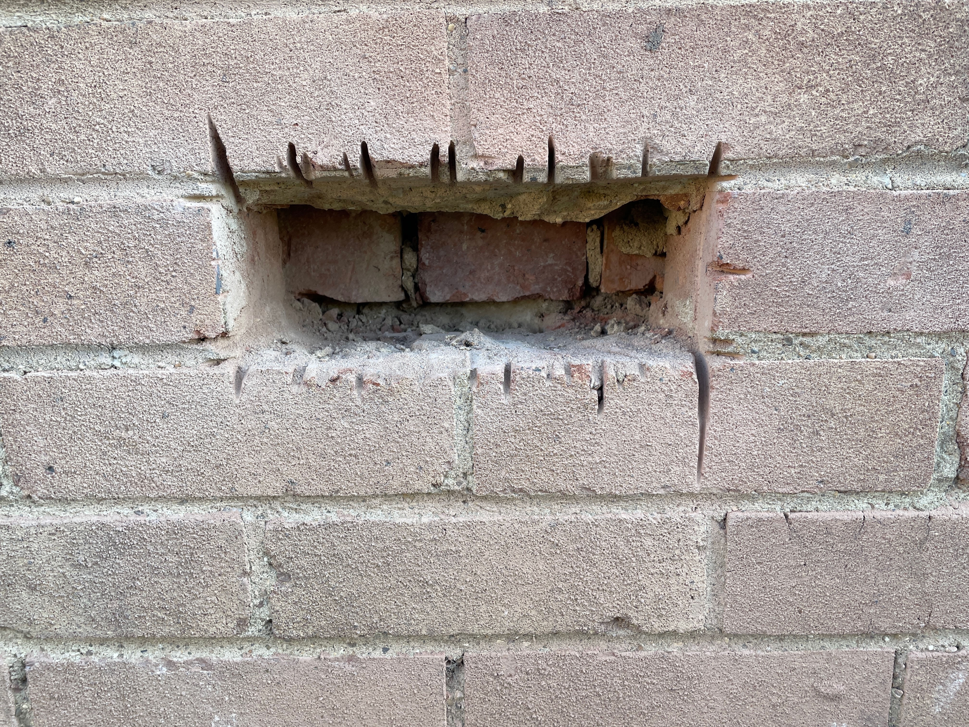 Opening-up inspection of a wall that appeared externally to be stretcher bond cavity construction but required direct inspection to confirm its build-up.